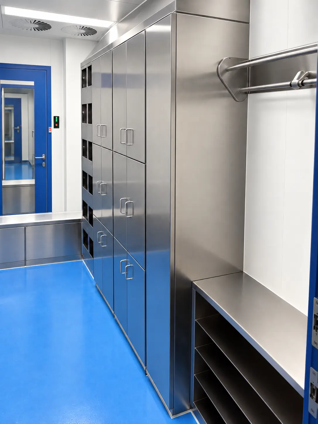 kleer-edelstahl-schrankwand-sitzbank Ensemble d’armoires en inox avec plusieurs portes, une niche ouverte avec assise, des compartiments de rangement et une tringle à vêtements.